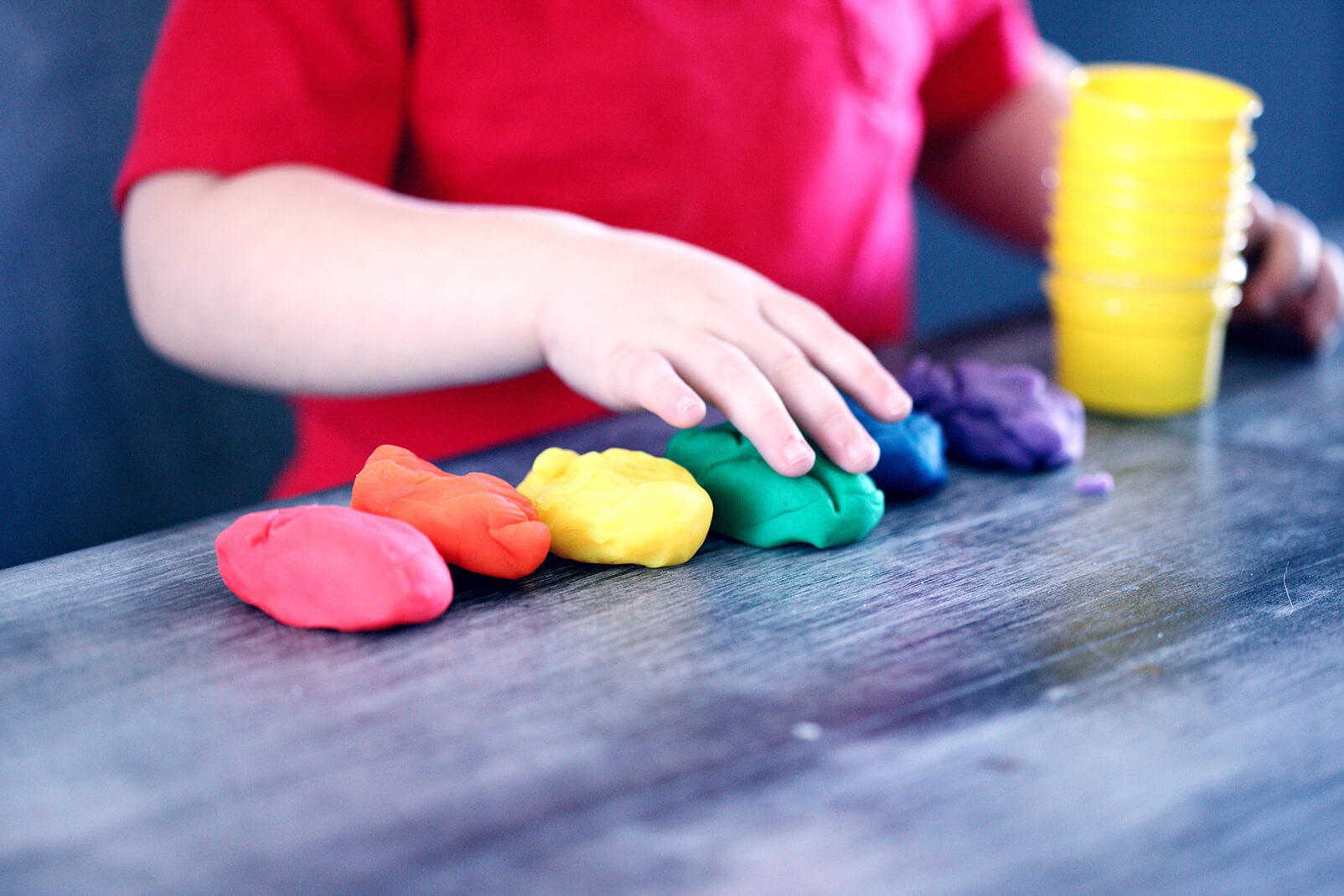 a child plays with brightly coloured balls of play dough.